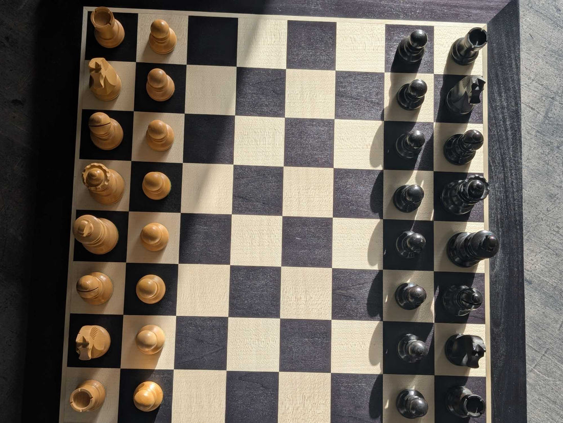 Plateau d'échecs noir et érable vu du dessus, pièces disposées sur les bords
